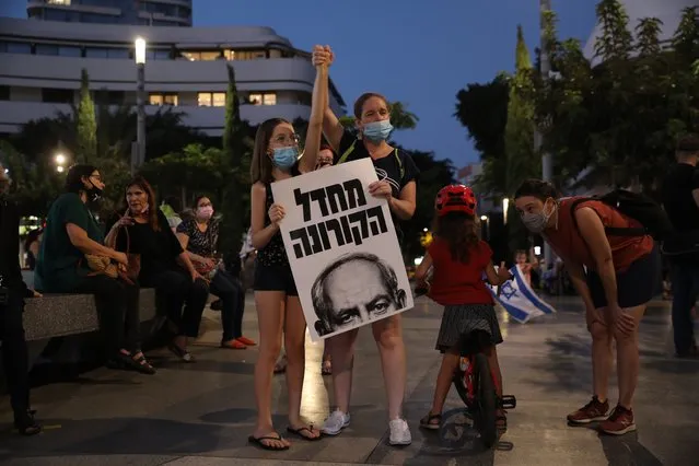 Israeli people carry a placard that reads in Hebrew “Coronavirus neglect” during a protest against Israeli Prime Minister Benjamin Netanyahu during a national lockdown, in Dizengoff square, Tel Aviv, Israel, 08 October 2020. Netanyahu faces an on going trial with indictments filed against him by the State Attorney's Office on charges of fraud, bribery and breach of trust. (Photo by Abir Sultan/EPA/EFE)