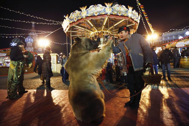 An artiste performs with a bear on the first day of a fair organized by GUM departmental store for the upcoming Christmas and New Year celebrations at Moscow's Red Square, November 29, 2014. (Photo by Maxim Zmeyev/Reuters)