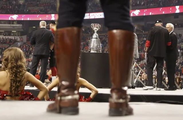 The Grey Cup is seen through the legs of a Royal Canadian Mounted Police officer during the presentation ceremony to the Calgary Stampeders following their victory over the Hamilton Tiger Cats in the CFL's 102nd Grey Cup football championship in Vancouver, British Columbia, November 30, 2014. (Photo by Andy Clark/Reuters)