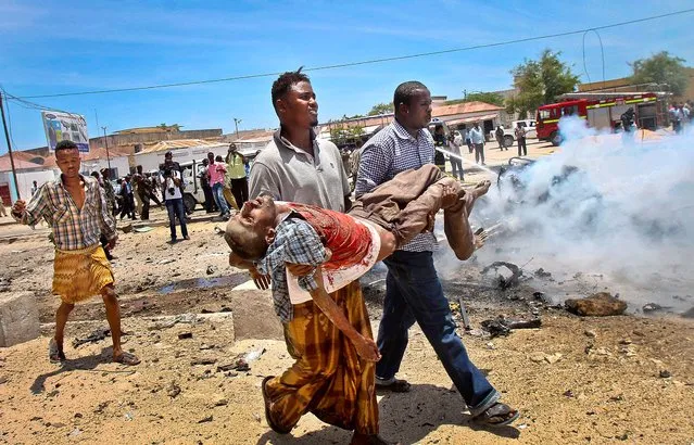 Men carry a seriously wounded man after a car bomb blast close to the Somali government's headquarters in the capital Mogadishu, on March 18, 2013. An explosives-laden car that apparently was targeting a truck full of government officials instead hit a civilian car and exploded, setting a nearby mini-bus on fire and killing at least seven people. (Photo by Farah Abdi Warsameh/Associated Press)