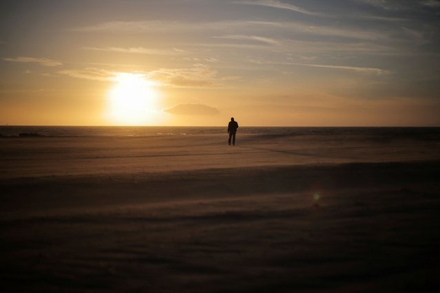 A man walks along the beach during a windy afternoon in Venice Beach, Los Angeles, California on February 12, 2025. (Photo by Daniel Cole/Reuters)