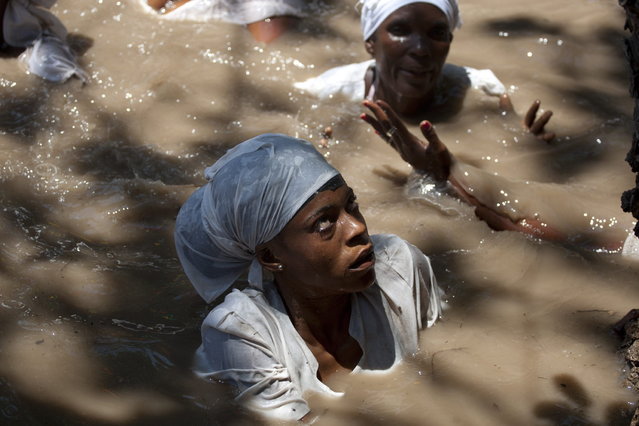 Voodoo followers wearing white swim in a sacred pool during a Voodoo ceremony in Souvenance, Haiti, Sunday, March 31, 2013. Hundreds of Voodoo followers travel to Souvenance over Easter weekend to show their devotion to the spirits. Voodoo was brought to Haiti by slaves from West Africa and is one of Haiti's three recognized religions. (Photo by Dieu Nalio Chery/AP Photo)