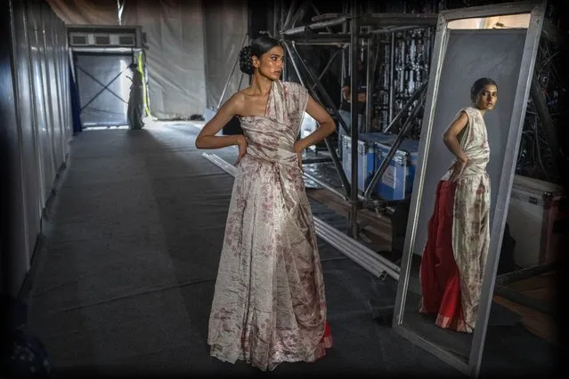 A model looks in a mirror as she waits on backstage for the start of a show during the Lakme Fashion Week X FDCI in Mumbai, India, Thursday, March 9, 2023. (Photo by Rafiq Maqbool/AP Photo)