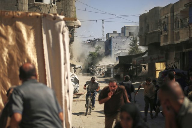 Palestinians run for cover during an Israeli military strike on a building in Gaza City, Saturday, September 13, 2025. (Photo by Yousef Al Zanoun/AP Photo)