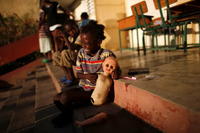 A girl plays with a doll in a partially destroyed school used as a shelter after Hurricane Matthew hit Jeremie, Haiti, October 12, 2016. (Photo by Carlos Garcia Rawlins/Reuters)