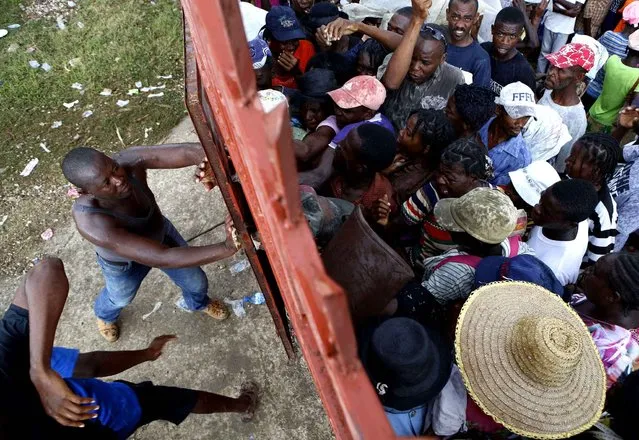 Security closes the gate on people trying to enter a yard where food distribution was to take place, in Maniche, Haiti, Monday, October 17, 2016. Tensions were rising Monday afternoon in Maniche when the food delivery still had not arrived. People said they had been told the distribution would be the day before, and some had walked six hours and then had to wait overnight, while others had spent their last money on public transport to arrive. (Photo by Rebecca Blackwell/AP Photo)