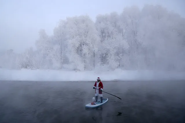 SUP_Novosibirsk stand up paddle boarding club founder Yevgeny Popov in a Santa Claus costume SUP surfs on a confluent of the Ob River in Novosibirsk, Russia on December 27, 2020. (Photo by Kirill Kukhmar/TASS)