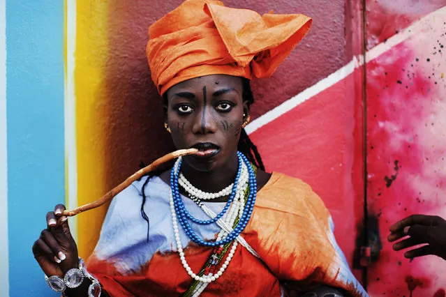 An actress from the Dseu Renaissance de Pikine theater group wearing traditional Toukouleur make-up and chewing a stick toothbrush waits for rehearsal to begin at a local community center at the slum neighbourhood of Pikine in Senegal's capital Dakar, November 7, 2009. (Photo by Finbarr O'Reilly/Reuters)