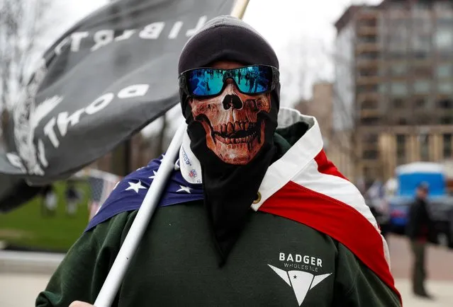 A man wearing a mask poses as demonstrators protest the extension of the emergency Safer at Home order by State Governor Tony Evers to slow the spread of the coronavirus disease (COVID-19), outside the State Capitol building in Madison, Wisconsin, U.S., April 24, 2020. (Photo by Shannon Stapleton/Reuters)