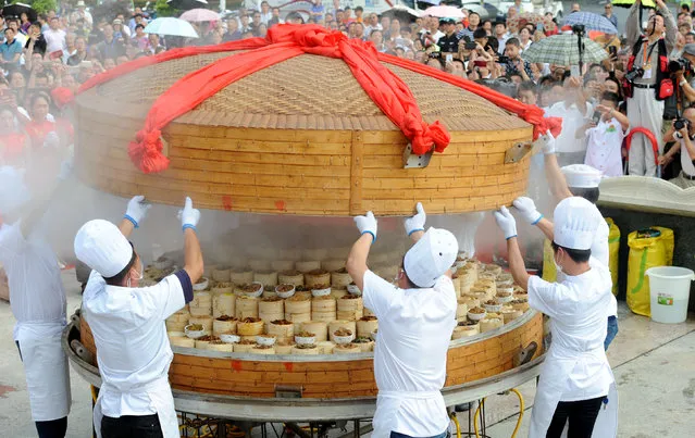 Chefs lift the lid of a giant food steamer during a steamed dish competition in Tianmen, Hubei province, China May 27, 2018. (Photo by Reuters/China Daily)
