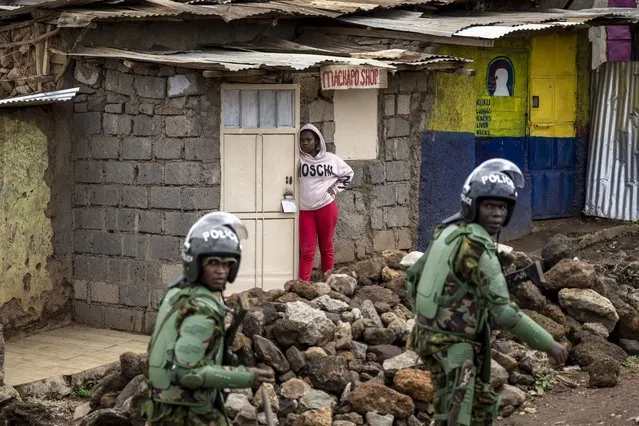 A woman looks out from a food shop as Kenyan riot police chase rock-throwing opposition protesters in the Kibera slum of the capital Nairobi, Kenya Tuesday, May 2, 2023. (Photo by Ben Curtis/AP Photo)