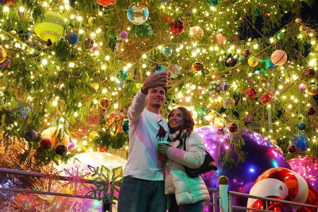 Marlon Rangel, left, and his girlfriend Evelyn Rodriguez, right, make a selfie as they stand in front of a christmas tree at Sundance Square Tuesday, December 2, 2025, in Fort Worth, Texas. (Photo by Tony Gutierrez/AP Photo)