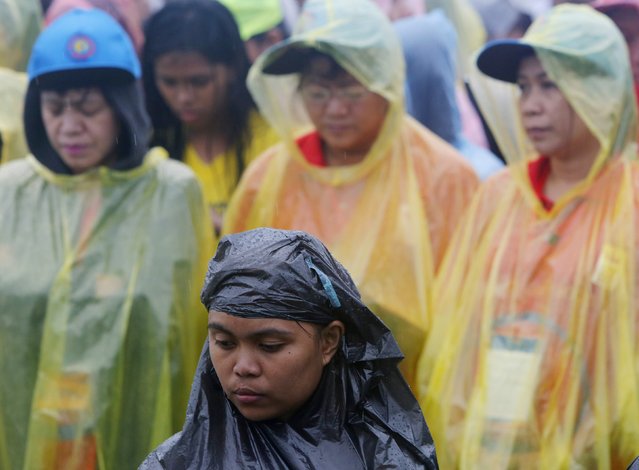 People wait in the rain for Pope Francis to lead an open-air Mass in Manila January 18, 2015. (Photo by Paul Barker/Reuters)