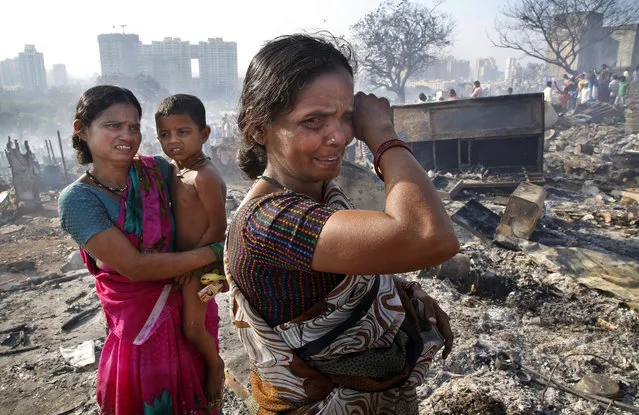 Women cry as they look for reusable household materials after fire broke at slums in Kadivali area of Mumbai, India, Monday, Dec. 7, 2015. Hundreds of homes were reportedly destroyed as fire tenders labored to reach the source in the heavily congested area. (AP Photo/Rajanish Kakade)