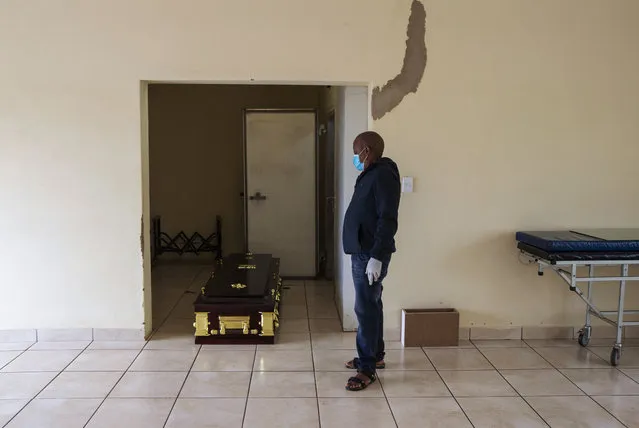 A mortuary worker stands next to a coffin carrying the body of a person who died of COVID-19 ahead of a funeral home in Vereeniging, east of Johannesburg, South Africa, Saturday, February 6, 2021. (Photo by Themba Hadebe/AP Photo)