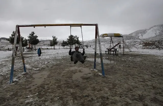 A boy plays on swing while visiting Hanna Lake after a snowfall on the outskirts of Quetta January 21, 2015. (Photo by Naseer Ahmed/Reuters)