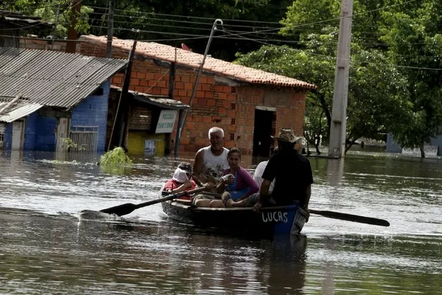 Men travel on a boat near flood-affected houses in Asuncion, December 20, 2015. (Photo by Jorge Adorno/Reuters)