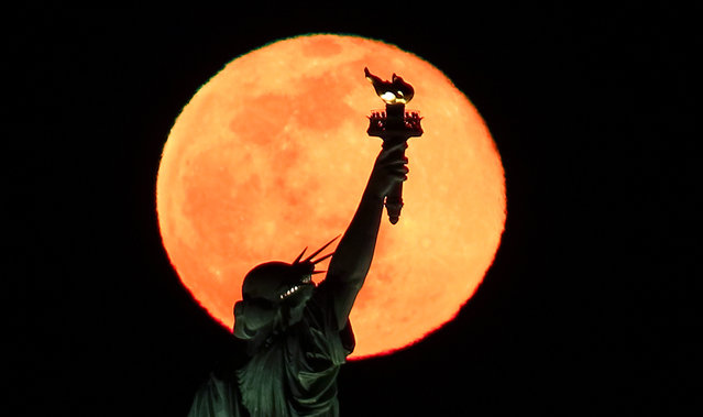 The full Snow Moon rises behind the Statue of Liberty in New York City on February 27, 2021 as seen from Jersey City, New Jersey. (Photo by Gary Hershorn/Getty Images)