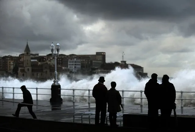 People look at waves crashing against the seawall on the San Lorenzo beach in Gijon, northern Spain, January 22, 2015. (Photo by Eloy Alonso/Reuters)
