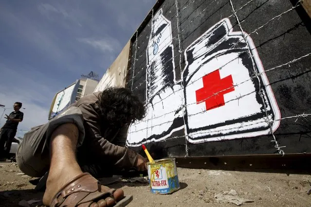 Artist Murad Subai paints graffiti depicting a bottle of water, medicine and a loaf of bread on a street in Sanaa December 31, 2015. The graffiti is part of a campaign titled "Wreckage", which focuses on the issue of the blockade imposed on cities by the war sides and on Yemen by the Saudi-led coalition forces. (Photo by Mohamed al-Sayaghi/Reuters)