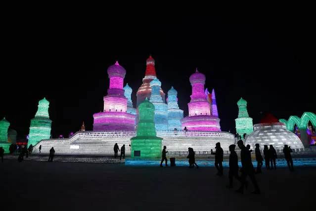 People walk past ice sculptures illuminated by coloured lights on the opening day of the Harbin International Ice and Snow Festival in the northern city of Harbin, Heilongjiang province, China, January 5, 2016. (Photo by Aly Song/Reuters)