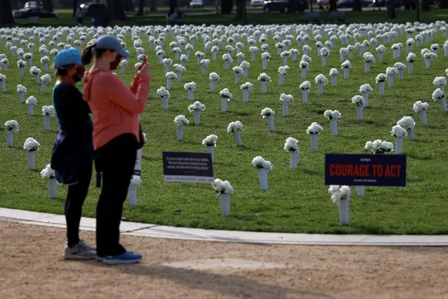 Visitors take pictures of the new Gun Violence Memorial, an installation featuring 38,000 silk white roses in 4,000 vases to commemorate the roughly 40,000 Americans who die annually in gun violence, on the National Mall in Washington, U.S., April 14, 2021. (Photo by Carlos Barria/Reuters)