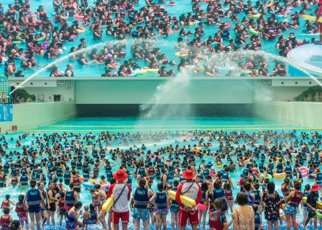 People swim under a giant screen at an indoor swimming pool on a hot day in Chengdu, Sichuan province, China on August 12, 2018. (Photo by Reuters/China Stringer Network)