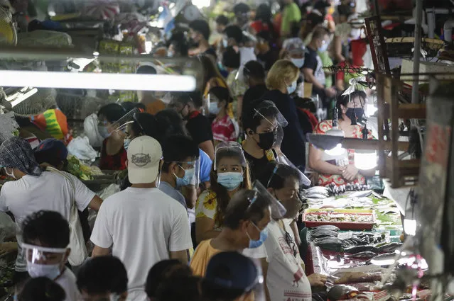 Poeple wearing face masks and face shields to prevent the spread of the coronavirus buy food at the Munoz market in Quezon city, Philippines as they prepare for a stricter lockdown on Sunday March 28, 2021. The government will start stricter lockdown measures next week as the country struggles to control an alarming surge in COVID-19 cases. (Photo by Aaron Favila/AP Photo)