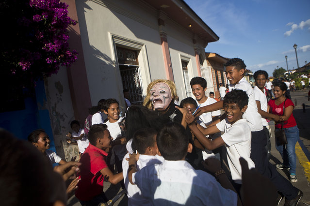 Children playfully accost a man dressed as a mythic character of Nicaraguan legend known as an“Aguizote”, during a symbolic burial of violence, as part of the International Poetry Festival of Granada, in Granada, Nicaragua, Wednesday, February 18, 2015. (Photo by Esteban Felix/AP Photo)