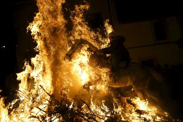 A woman rides a horse through the flames during the “Luminarias” annual religious celebration on the eve of Saint Anthony's day, Spain's patron saint of animals, in the village of San Bartolome de Pinares, northwest of Madrid, Spain, January 16, 2016. (Photo by Susana Vera/Reuters)