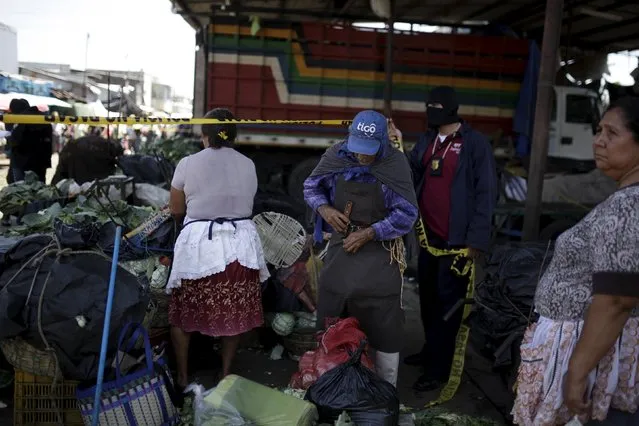 Sellers withdraw their produce as police investigators secure a crime scene at La Tiendona market in San Salvador, July 2, 2015. Miguel Angel Acevedo was killed by suspected gang members while he was selling potatoes at La Tiendona market, one of the most violent places in San Salvador, according to local media. (Photo by Jose Cabezas/Reuters)