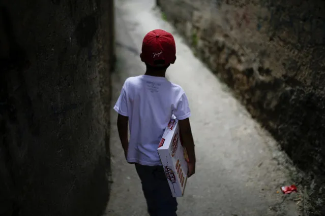 A boy walks with a toy received during toy distribution program with Miguel Pizarro, deputy of the Venezuelan coalition of opposition parties (MUD), in an alley at the slum of Petare in Caracas, Venezuela December 20, 2016. (Photo by Marco Bello/Reuters)
