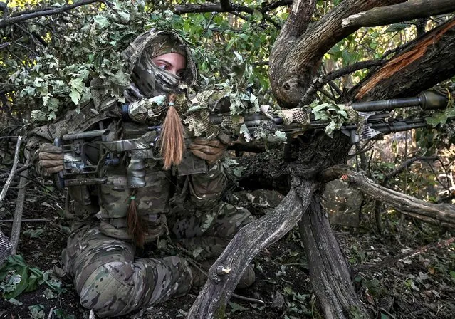 A sniper of Ukraine's 3rd Separate Assault Brigade takes a position during a reconnaissance mission, near Bakhmut, Ukraine on September 7, 2023. (Photo by Reuters/Stringer)