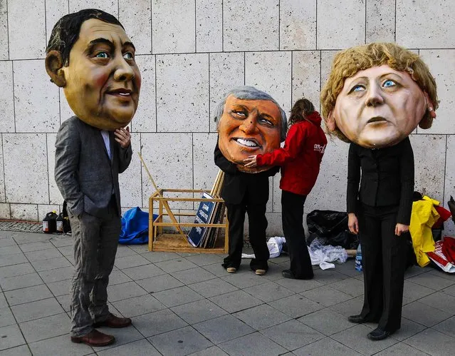 Environmental activists of “Campact!”, wear masks depicting leader of the German Social Democratic party (SPD) Sigmar Gabriel party leader of Christian Social Union (CSU) Horst Seehofer and leader of German Christian Democratic Union (CDU) Angela Merkel during a protest outside coalition talks at the CDU headquarters in Berlin, on November 13, 2013. (Photo by Tobias Schwarz/Reuters)