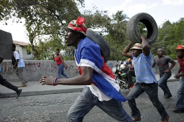 Two protesters carry tires during a demonstration called up by opposition groups in Port-au-Prince, Haiti, February 4, 2016. (Photo by Andres Martinez Casares/Reuters)