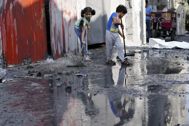 Palestinian children mop outside their home after an Israeli bombardment in the Maghazi refugee camp in the Gaza Strip on Sunday, November 5, 2023. (Photo by Hatem Moussa/AP Photo)
