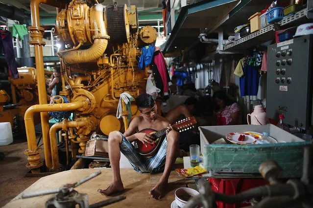 A boy plays a guitar in the hull of a tanker that was washed ashore in a particularly badly damaged part of Tacloban during Typhoon Haiyan on November 19, 2013 in Leyte, Philippines. (Photo by Dan Kitwood/Getty Images)