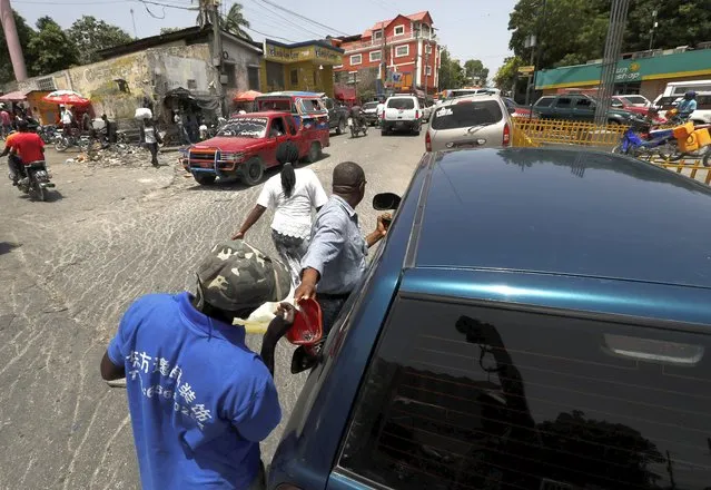 A young man fills a driver's tank with gasafter reselling it to him, in Port-au-Prince, Tuesday, July 13, 2021, almost a week after President Jovenel Moise was assassinated in his home. (Photo by Fernando Llano/AP Photo)