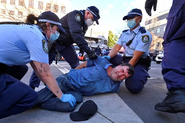 Police arrest a protester at a rally in Sydney on July 24, 2021, as thousands of people gathered to demonstrate against the city's month-long stay-at-home orders. (Photo by Steven Saphore/AFP Photo)