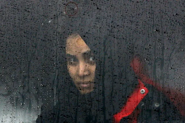 A migrant looks through a train window as migrants and refugees wait for their train to depart to Slovenia on their journey to western Europe at a refugee transit camp in Slavonski Brod, Croatia, February 10, 2016. (Photo by Darrin Zammit Lupi/Reuters)