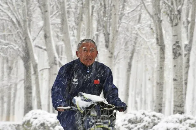 A man rides a bicycle in snow in Shenyang, northeast China's Liaoning Province on November 6, 2023. A cold front hit Shenyang on Monday, bringing heavy snow to the city. (Photo by Yang Qing/Xinhua News Agency)
