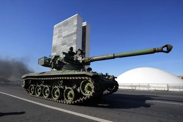 A tank drives past Congress as part of a convoy after it passed by Planalto presidential palace in Brasilia, Brazil, Tuesday, August 10, 2021. The convoy paraded by the palace on Tuesday, the day of a key congressional vote on a constitutional reform proposal supported by Bolsonaro that would add printed receipts to some of the nation’s electronic ballot boxes. (Photo by Eraldo Peres/AP Photo)