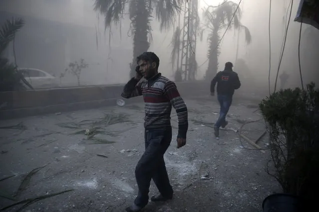 In this image released by World Press Photo titled “Aftermath of Airstrikes in Syria” by photographer Sameer Al-Doumy for AFP which won the first prize in the Spot News stories category shows a wounded man walking out of a dust cloud following reported airstrikes in the town of Hamouria, Syria, December 9, 2015. (Photo by Sameer Al-Doumy/AFP, World Press Photo via AP Photo)