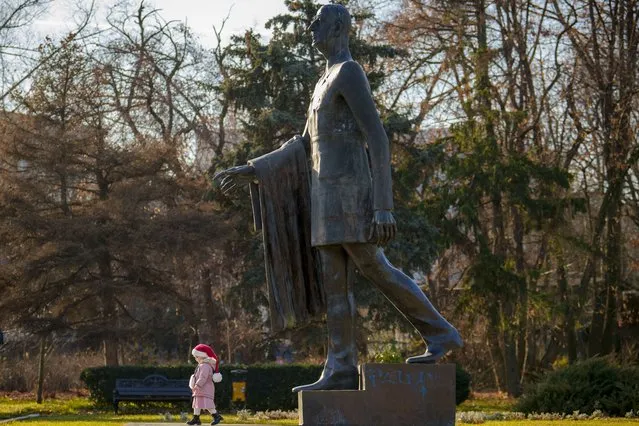 A child walks next to the statue of French statesman Charles de Gaulle in Bucharest, Romania, Tuesday, January 2, 2024. (Photo by Vadim Ghirda/AP Photo)