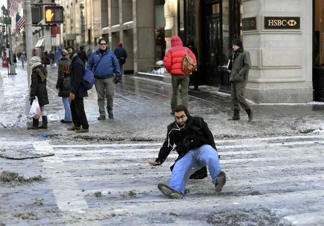 A man falls on the ice and snow along  5th Avenue January 22, 2014 in New York. The northeastern US shivered amid heavy snowfall and far below average temperatures in a storm that grounded thousands of flights and triggered traffic chaos. (Photo by Timothy Clary/AFP Photo)