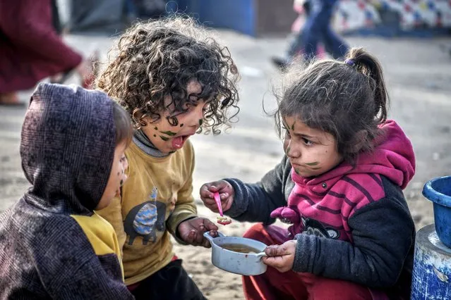 Palestinian kids eat warm meal from Tahrir Ebu Amsha (38) and her 12-year-old daughter Shahed at the camp as they endure harsh living conditions in Rafah, Gaza on January 17, 2024. (Photo by Abed Zagout/Anadolu via Getty Images)