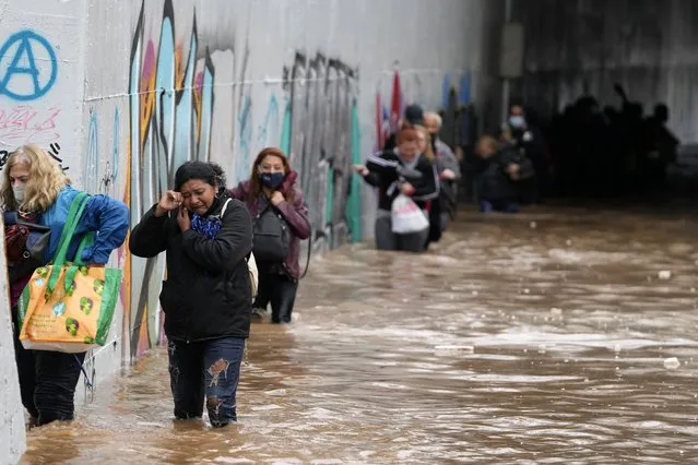 Passengers wade through high water after evacuating a bus stuck in a flooded underpass in southern Athens, Thursday, October 14, 2021. Storms have been battering the Greek capital and other parts of southern Greece, causing traffic disruption and some road closures. (Photo by Thanassis Stavrakis/AP Photo)