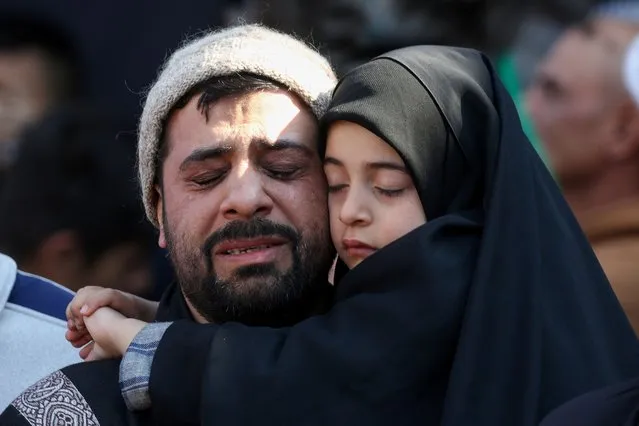 A Shi'ite Muslim man holds a child as he reacts during a commemoration marking the death anniversary of Imam Moussa al-Kadhim, in Baghdad, Iraq, on February 6, 2024. (Photo by Ahmed Saad/Reuters)