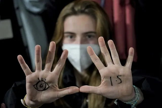A woman, with an eye drawn on her hand to show she is watching and 1.5 for countries to limit warming to 1.5 degrees Celsius, takes part in a protest inside a plenary corridor at the SEC (Scottish Event Campus) venue for the COP26 U.N. Climate Summit, in Glasgow, Scotland, Wednesday, November 10, 2021. The U.N. climate summit has entered its second week, and leaders from around the world are gathering to lay out their vision for addressing the common challenge of global warming. (Photo by Alberto Pezzali/AP Photo)