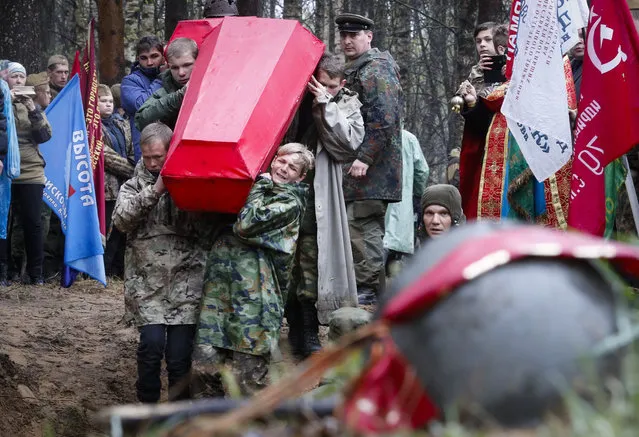 Members of volunteer search teams carry coffins with the remains of Soviet soldiers killed during World War II, during a reburial ceremony at the Sinyavino Heights memorial near the village of Sinyavino, 50 km (31 miles) east of St. Petersburg, Russia, Tuesday, May 7, 2019. Hundreds of people came to a World War II battleground outside St. Petersburg to bury the remains of 714 Soviet soldiers recovered by volunteer search teams. Forty one crimson coffins containing skulls and bones were solemnly buried at the Sinyavino Heights memorial as Russian war songs played and an honor guard fired a salute. (Photo by Dmitri Lovetsky/AP Photo)